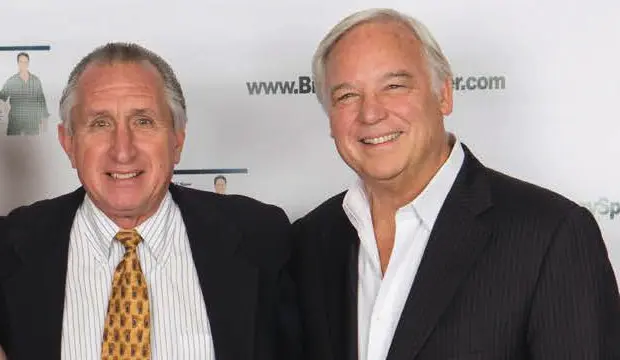 Two men smiling in formal attire.