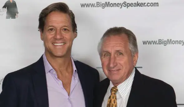 Two men smiling at a speaking event.