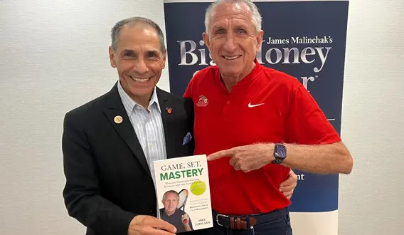 Two men smiling, holding a book.