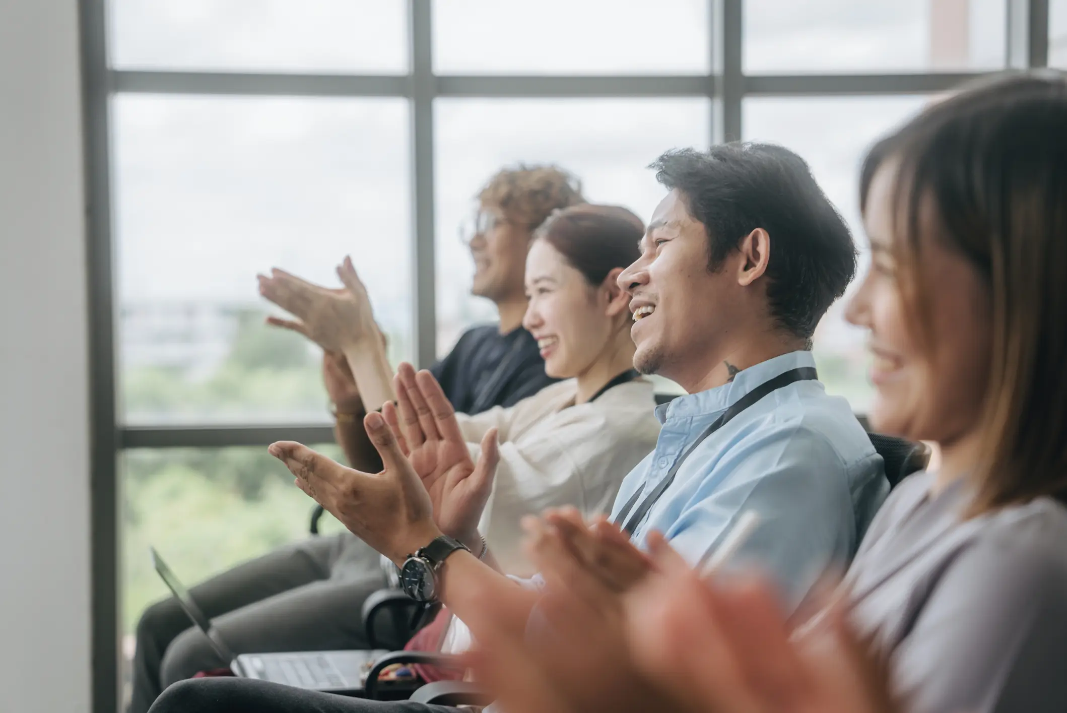 People sitting and applauding in a meeting.